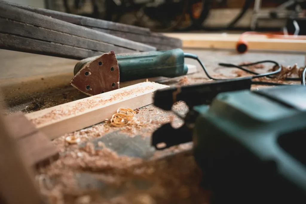 Lijadora multifunción sobre superficie de madera con virutas, ideal para bricolaje doméstico