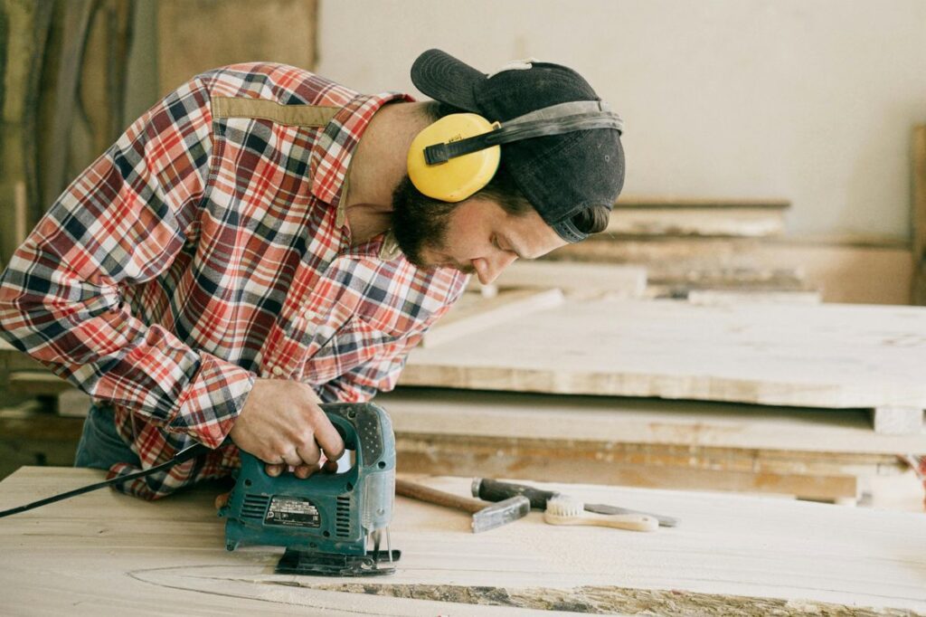 Hombre usando sierra de calar para cortar madera en taller de bricolaje
